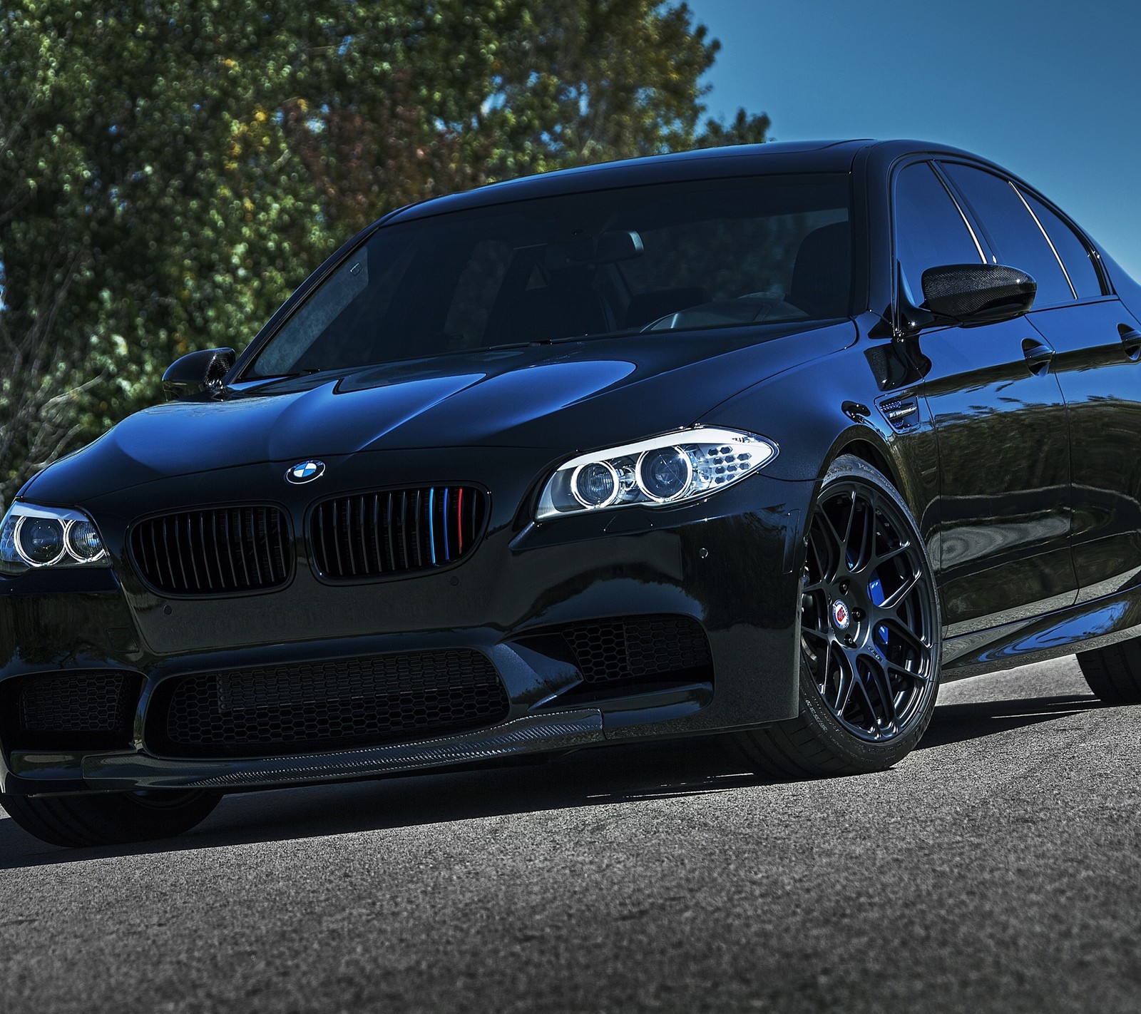 A close up of a black bmw car parked on a street (auto, bimmer, bmw, car, m5)