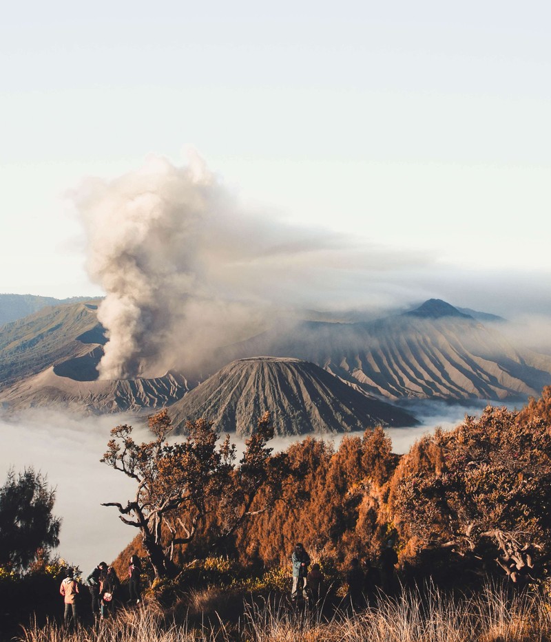 Люди стоят на холме, глядя на гору с дымом (гора бромо, mount bromo, вулкан, гора, вулканическая форма рельефа)