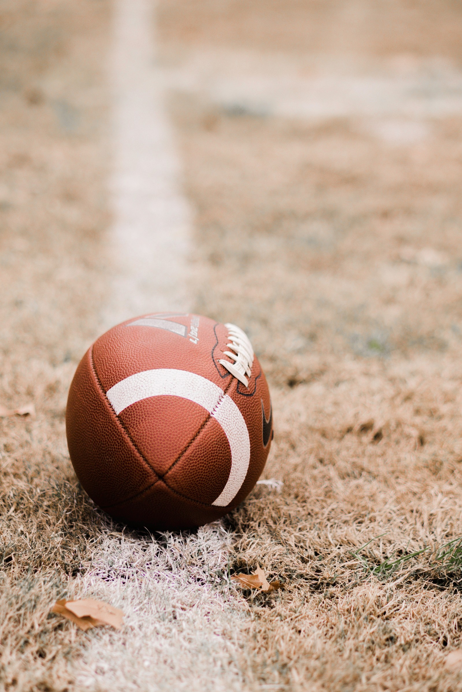 There is a football on the ground with a line in the background (american football, ball, football, team sport, soccer ball)