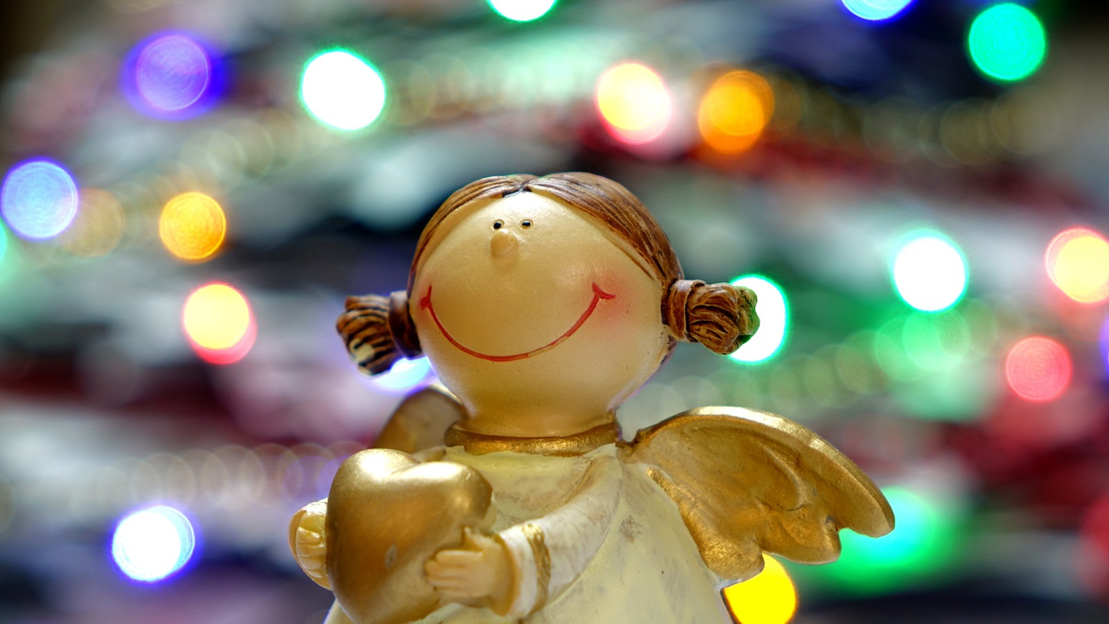 Eine kleine goldene engelstatue mit einem lächeln darauf (weihnachten, weihnachtslichter, heiligabend, geschenk, makrofotografie)