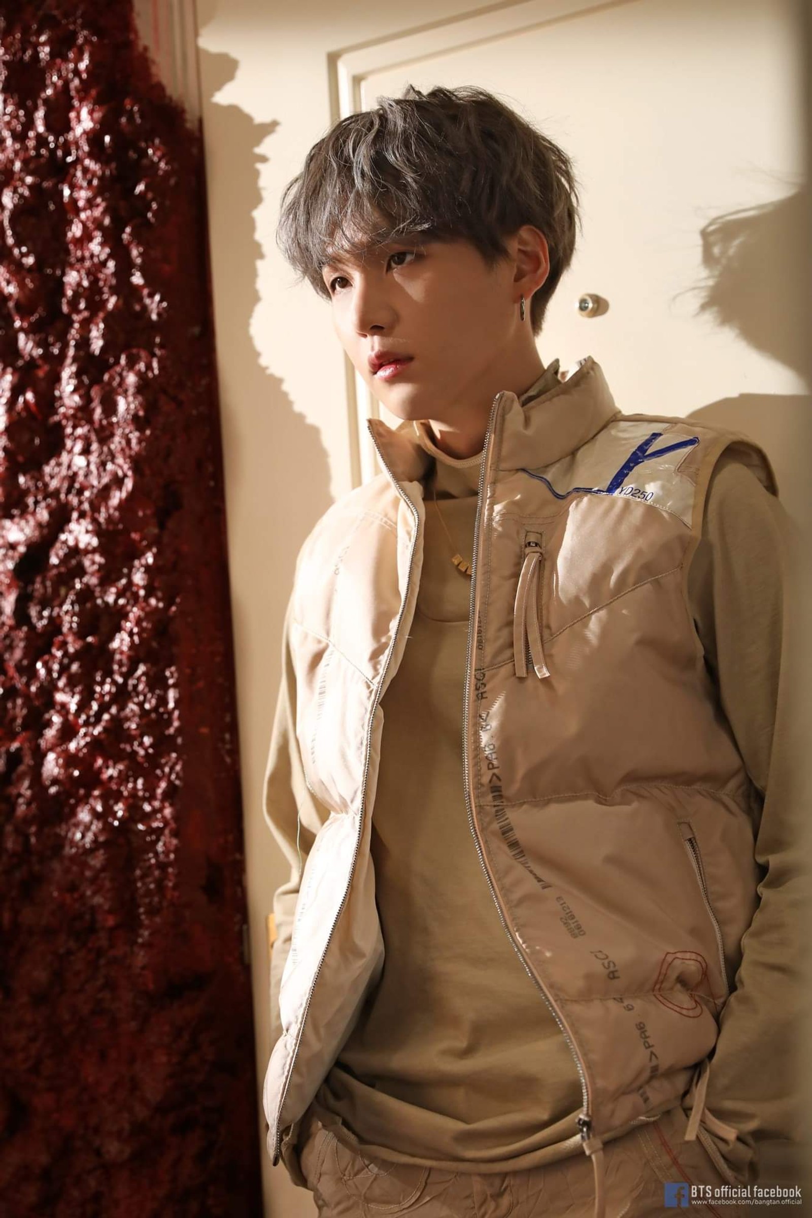 Homme arafed en veste beige se tenant devant un rideau rouge (bts, kpop, suga)