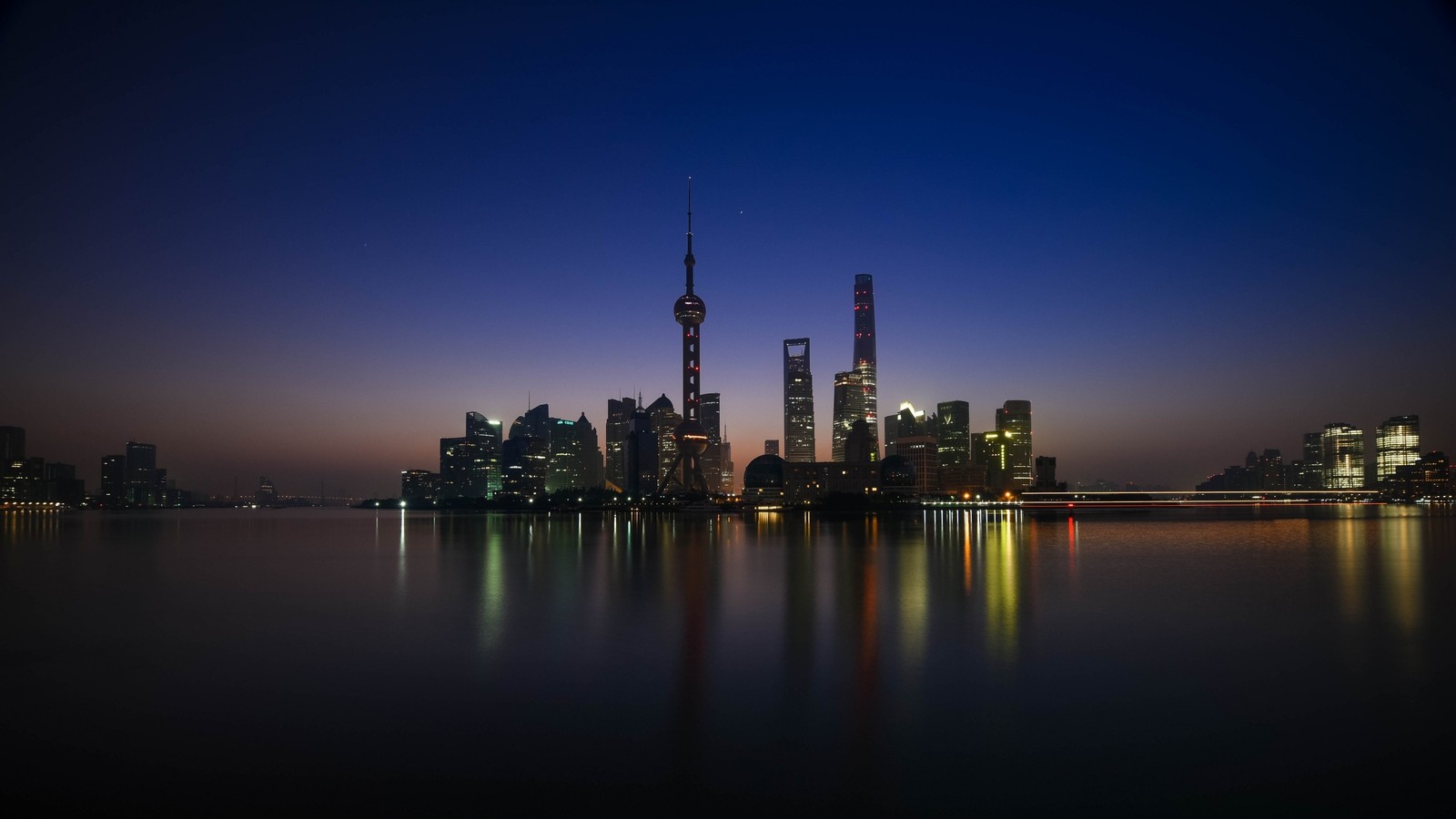 Vue aérienne d'une silhouette de ville la nuit avec un lac devant (shanghai, ville, horizon, paysage urbain, réflexion)