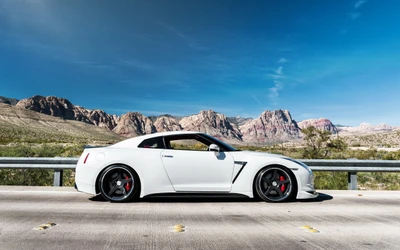 Sleek white Nissan GT-R sports car parked against a stunning mountainous backdrop.