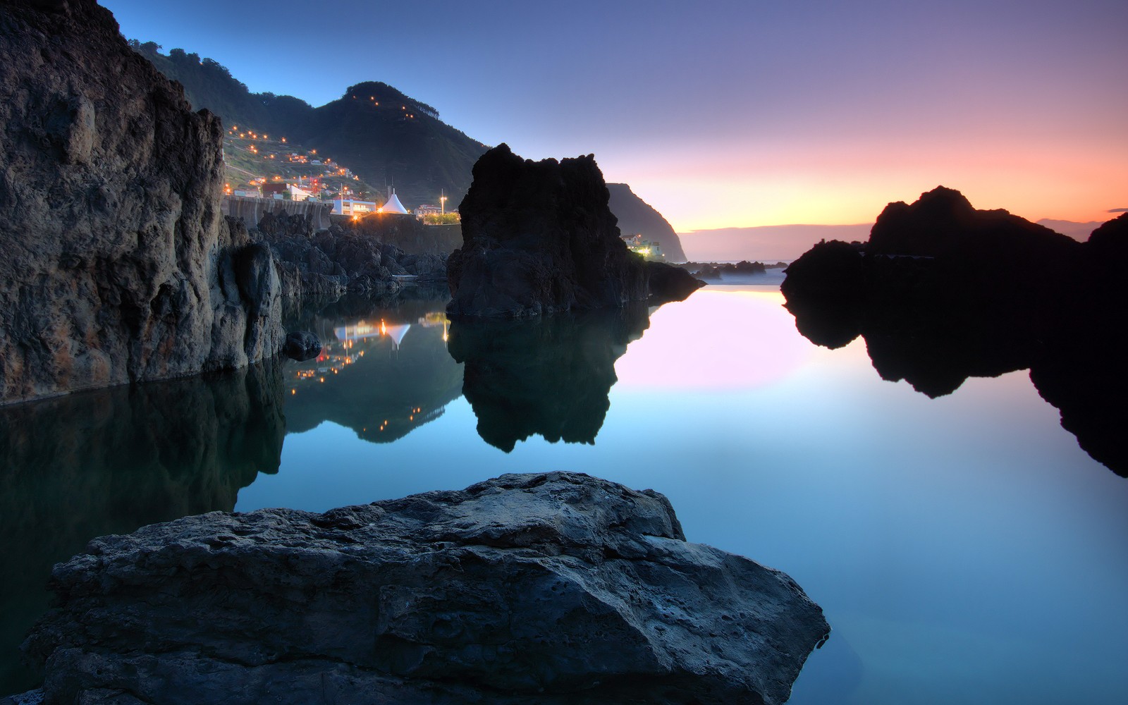 A view of a body of water with rocks in the foreground (reflection, nature, water, rock, sea)