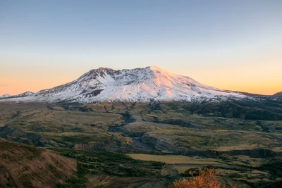 El Monte St. Helens al amanecer, mostrando su pico cubierto de nieve y la naturaleza circundante en un paisaje pintoresco de Oregón.