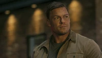 Alan Ritchson como el decidido Reacher en un entorno urbano áspero