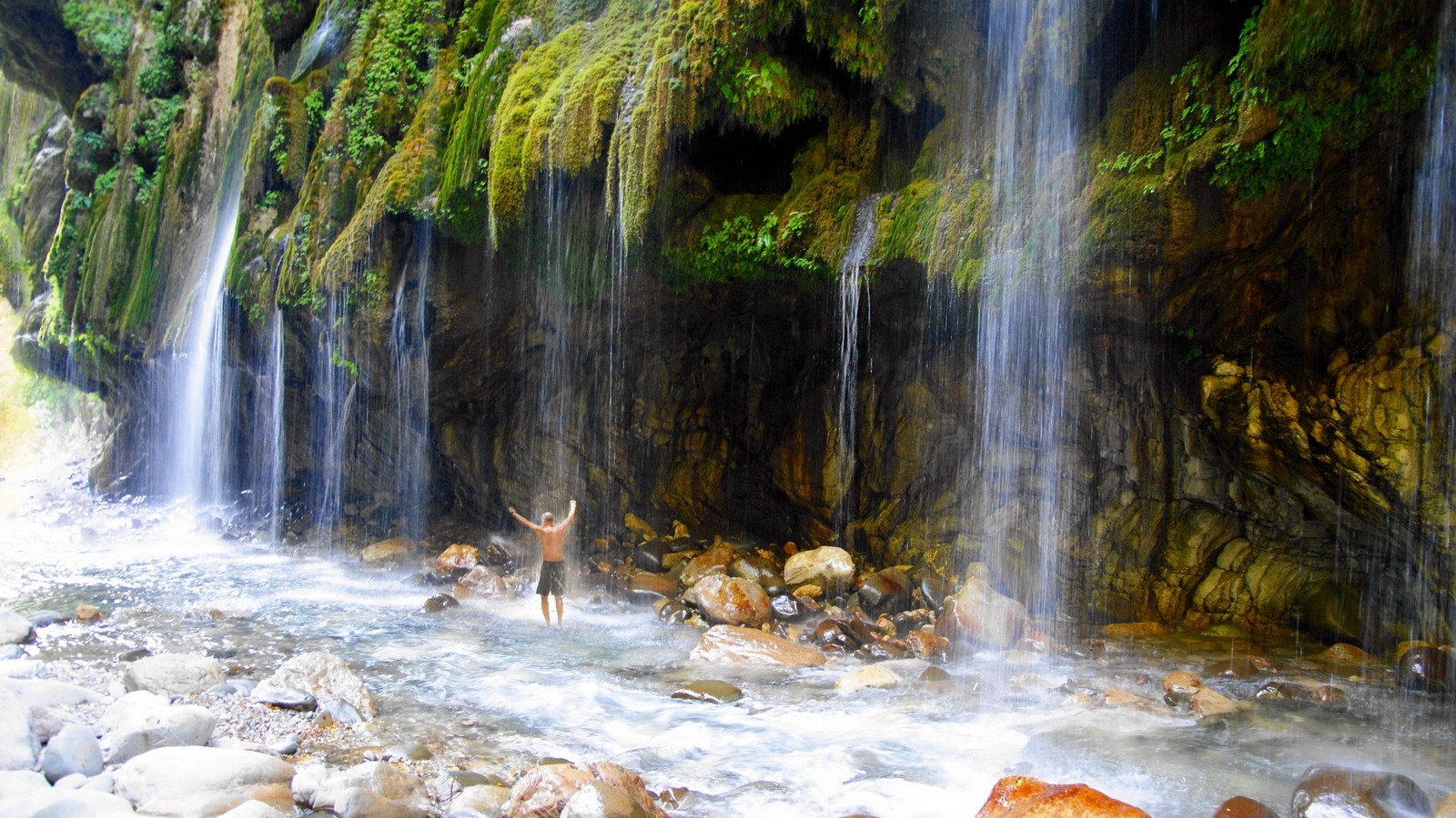 Hay un ciervo de pie en el agua cerca de una cascada (grecia, cascada, cuerpo de agua, recursos hídricos, naturaleza)