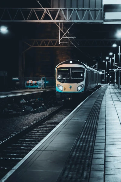 Tren moderno en estación nocturna con vías iluminadas