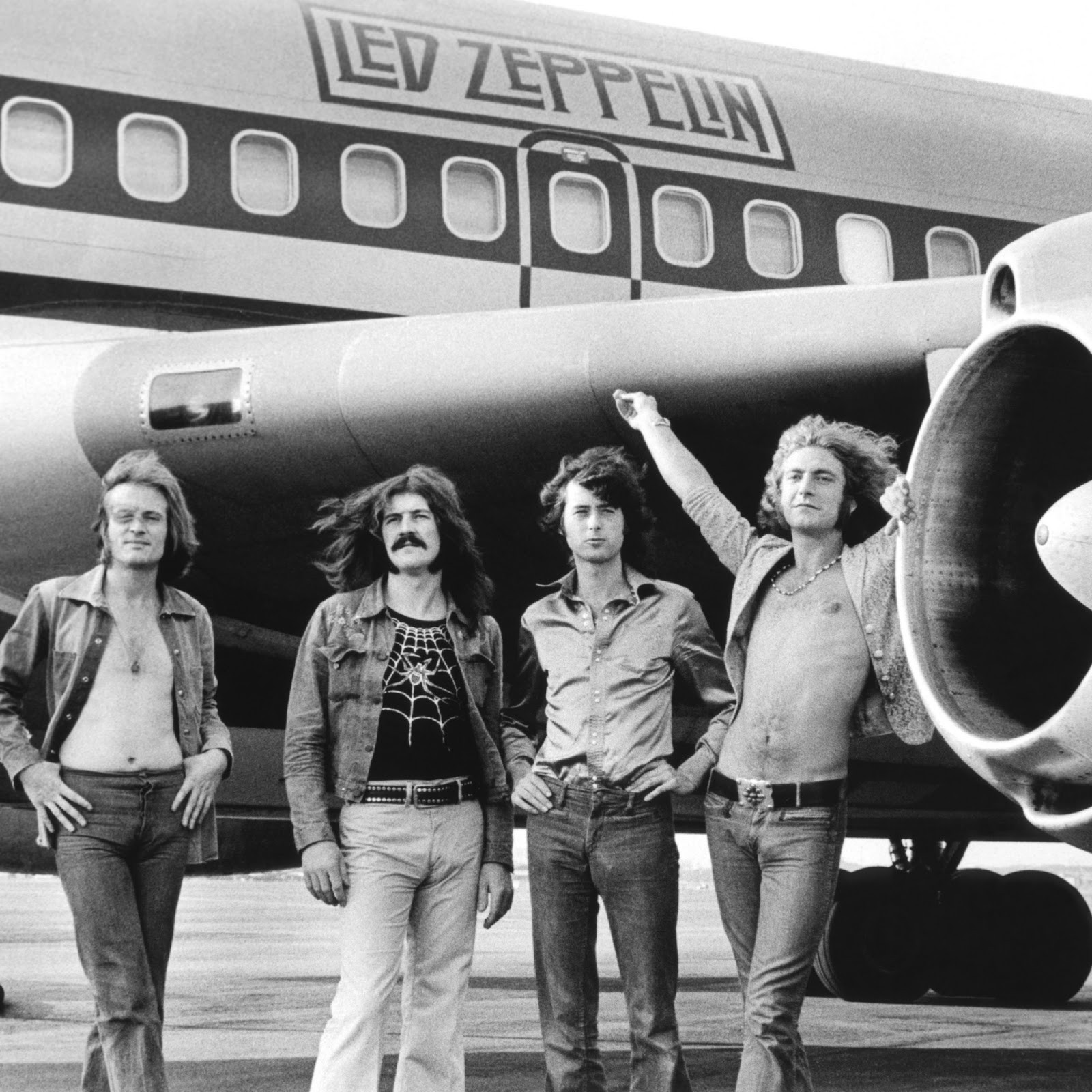 Grupo árabe de hombres de pie frente a un avión (led zeppelin, robert plant, jimmy page, avión, música)