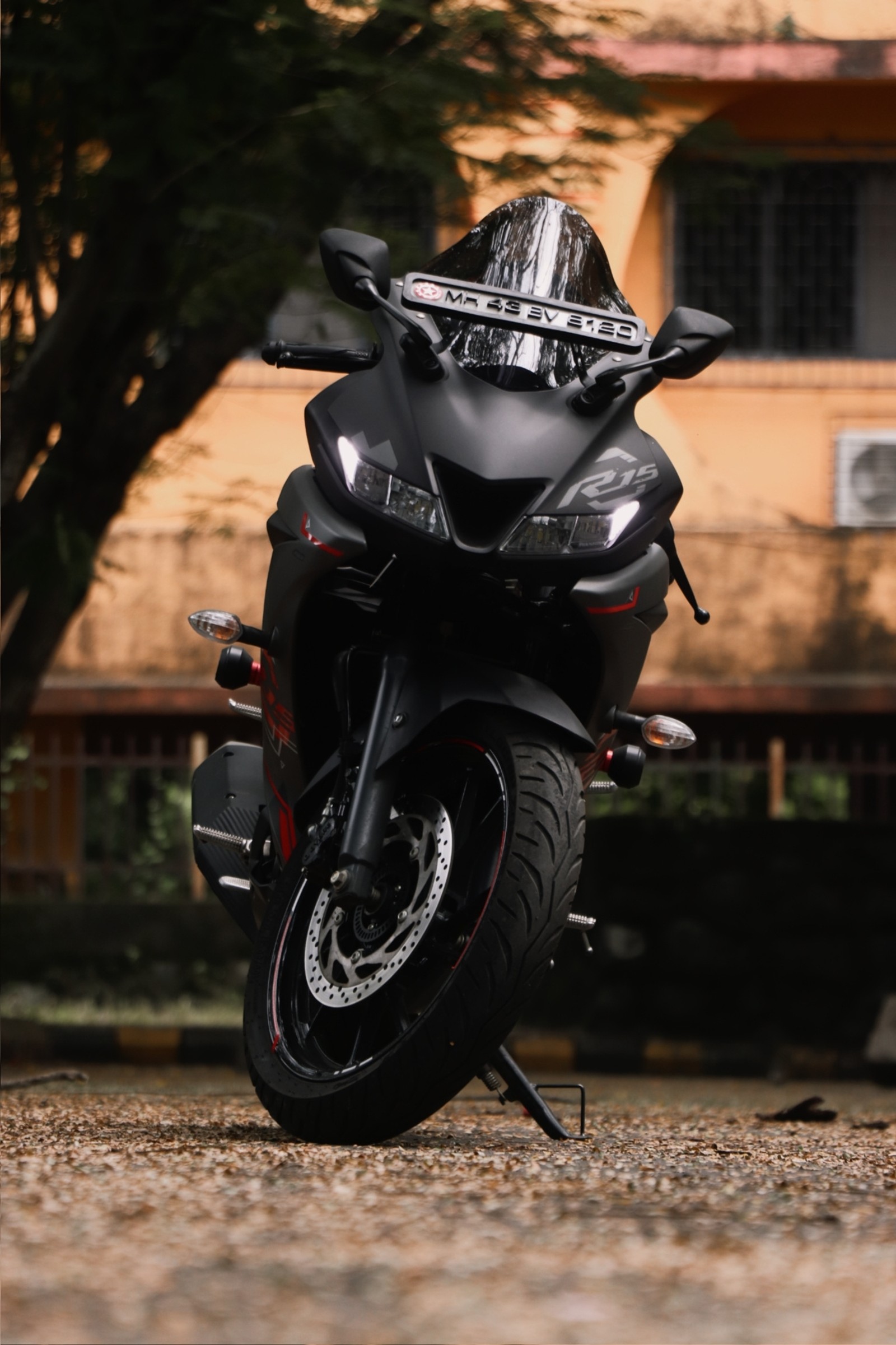 Una motocicleta está estacionada en el suelo frente a un edificio (r15 v3, r15v3)