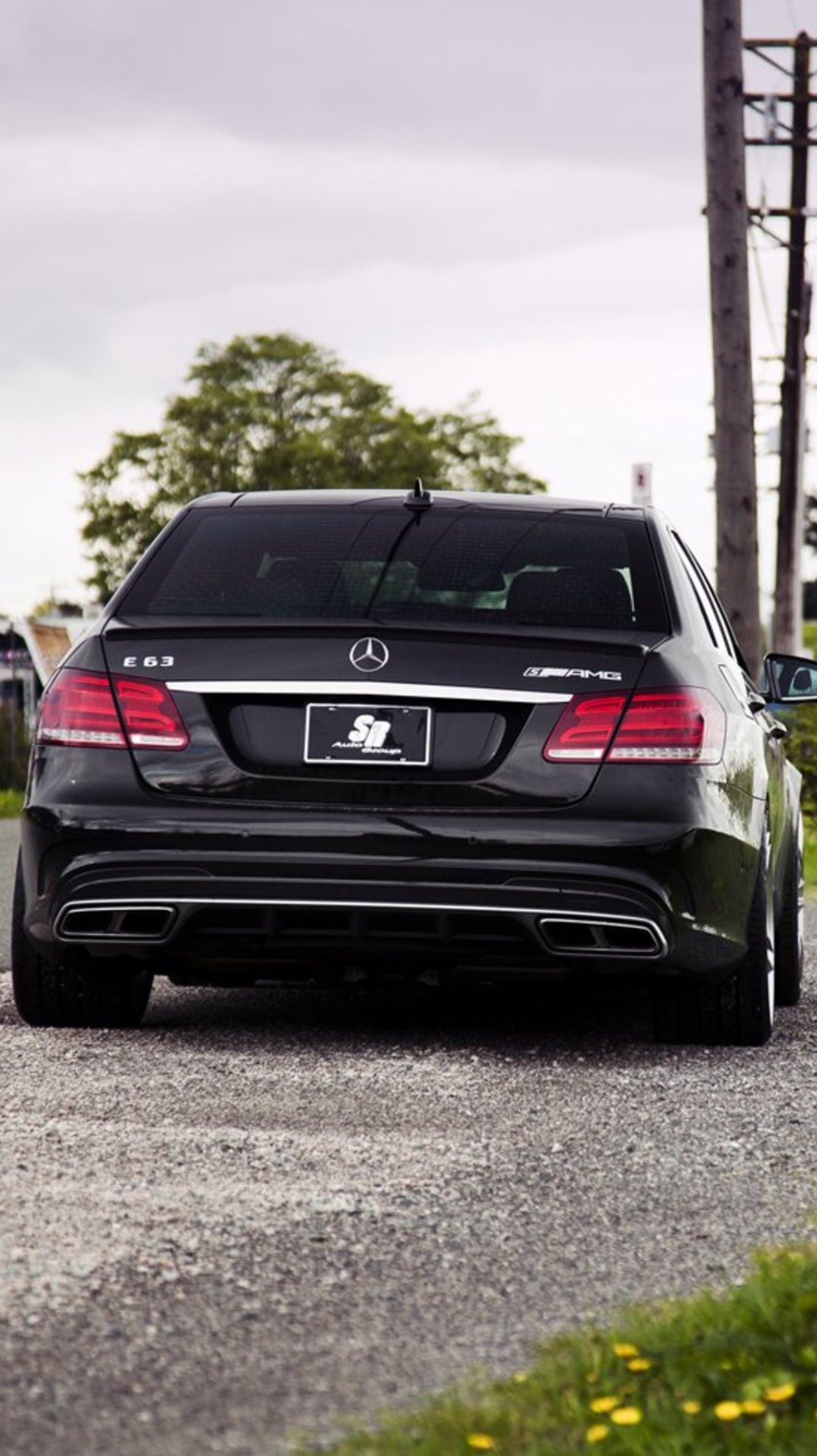 Un coche arafed negro estacionado en un camino de grava cerca de un poste de luz (amg mercedes, atrás, negro, coche)