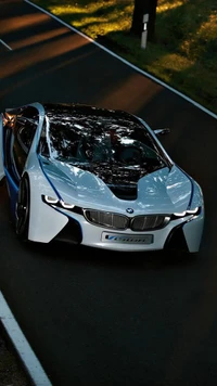 2018 BMW i8 in sleek white design on a winding road surrounded by greenery.