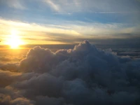 Golden Horizon: Cumulus Clouds Embracing a Majestic Sunset Sky