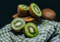 Rodajas de kiwi fresco sobre madera rústica y tela a cuadros verdes