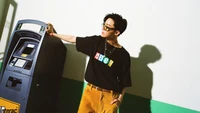 J-Hope de BTS posant avec style à côté d'un distributeur automatique, mettant en avant une esthétique moderne et ludique.