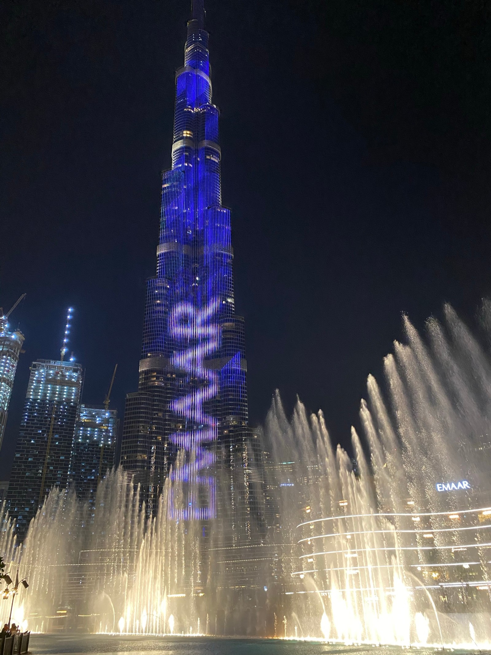 Fonte árabe em frente à torre burj khalifa com luzes azuis (dubai, burj khalifa, marco, água, noite)