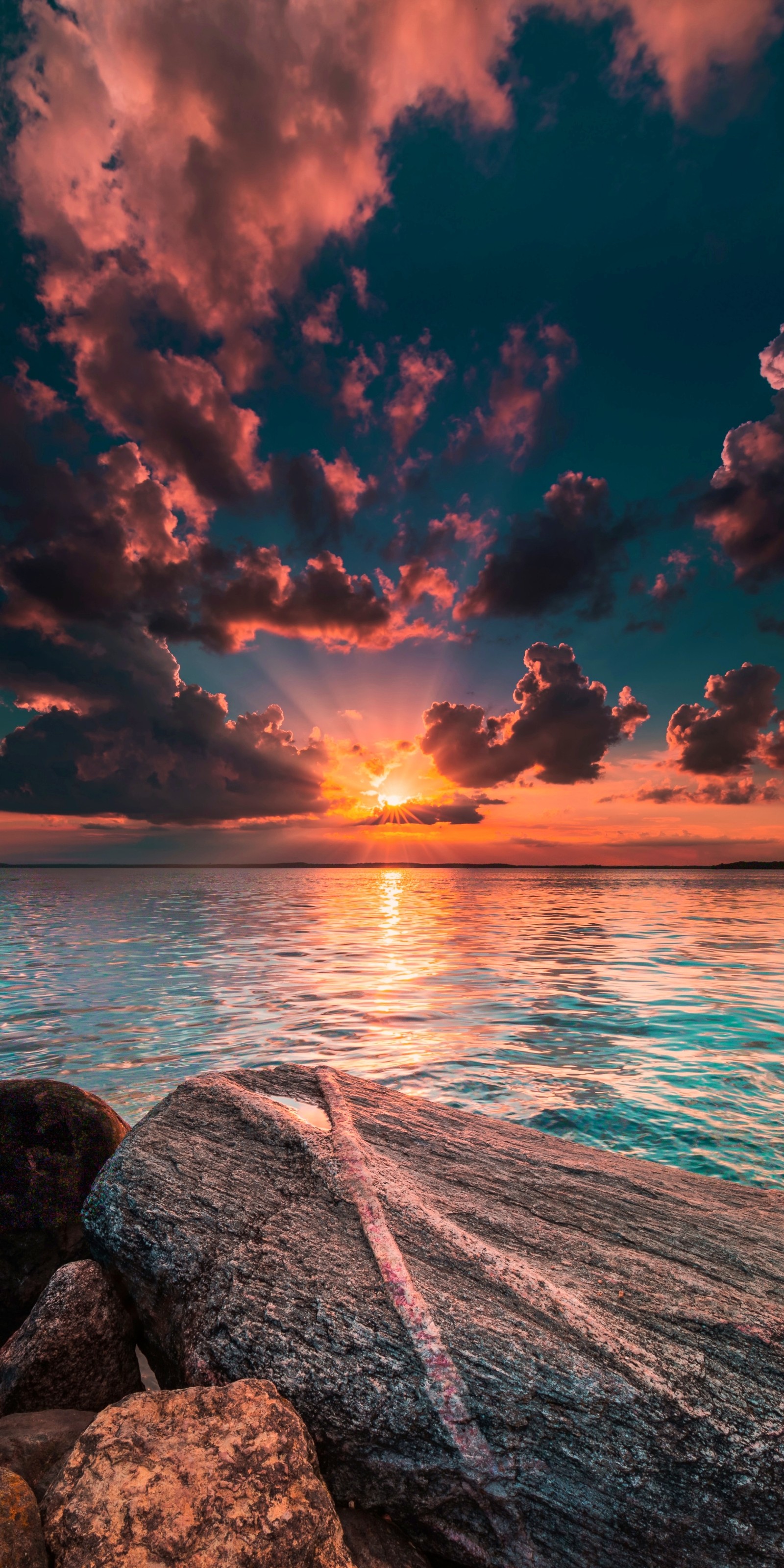 Coucher de soleil sur l'océan avec des rochers et un ciel nuageux (ensoleillement, paysage, lumière, nature, eau)