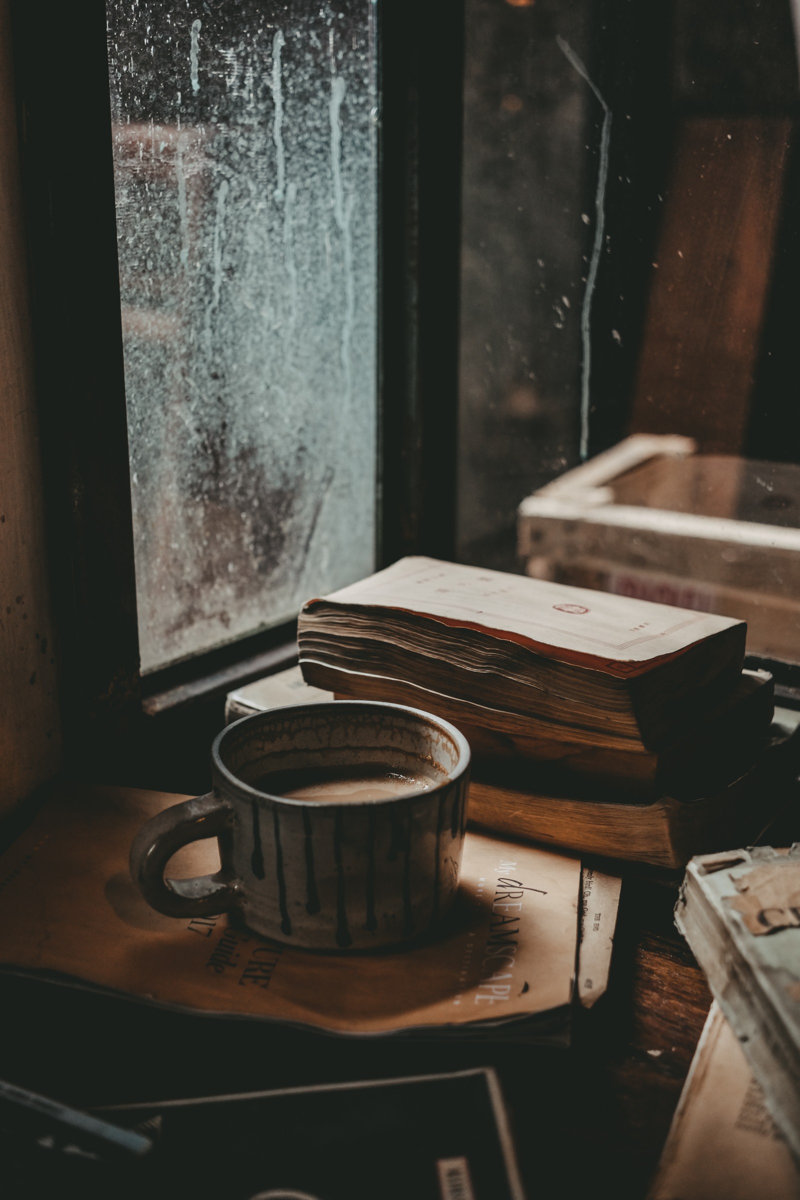 Auf einem tisch steht eine tasse kaffee neben einem buch (kaffee, holz, zimmer, stillleben, tisch)