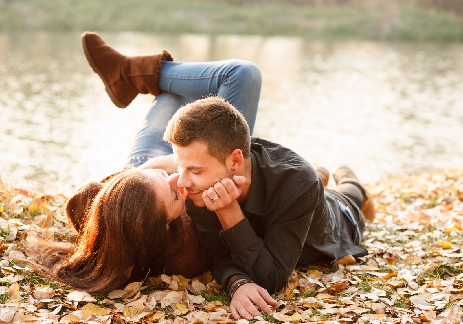 Arafed couple laying on the ground in the fall leaves (romance, couple, people in nature, love, leaf)