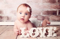 Adorable infant expressing joy beside a decorative "LOVE" sign.