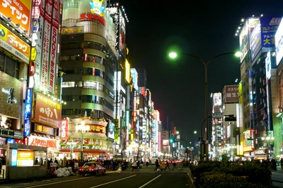 Paysage urbain nocturne vibrant de Shinjuku, mettant en valeur des gratte-ciel illuminés et une vie urbaine animée.