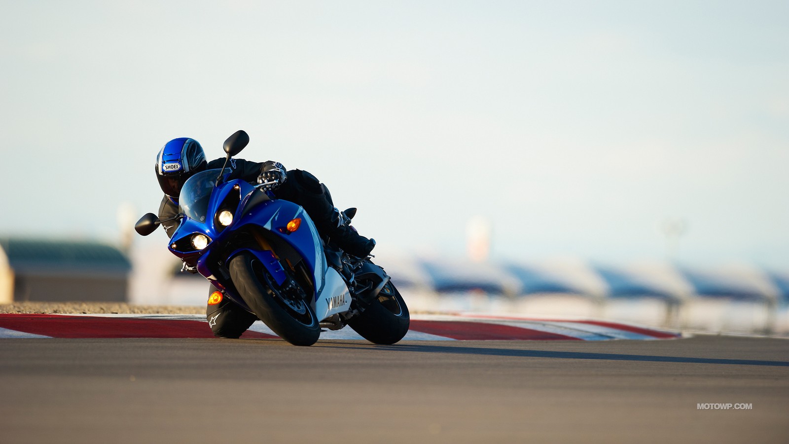 Ein mann fährt mit einem motorrad auf einer strecke mit helm (motorad, yamaha motor company, yamaha corporation, rennstrecke, extremsport)