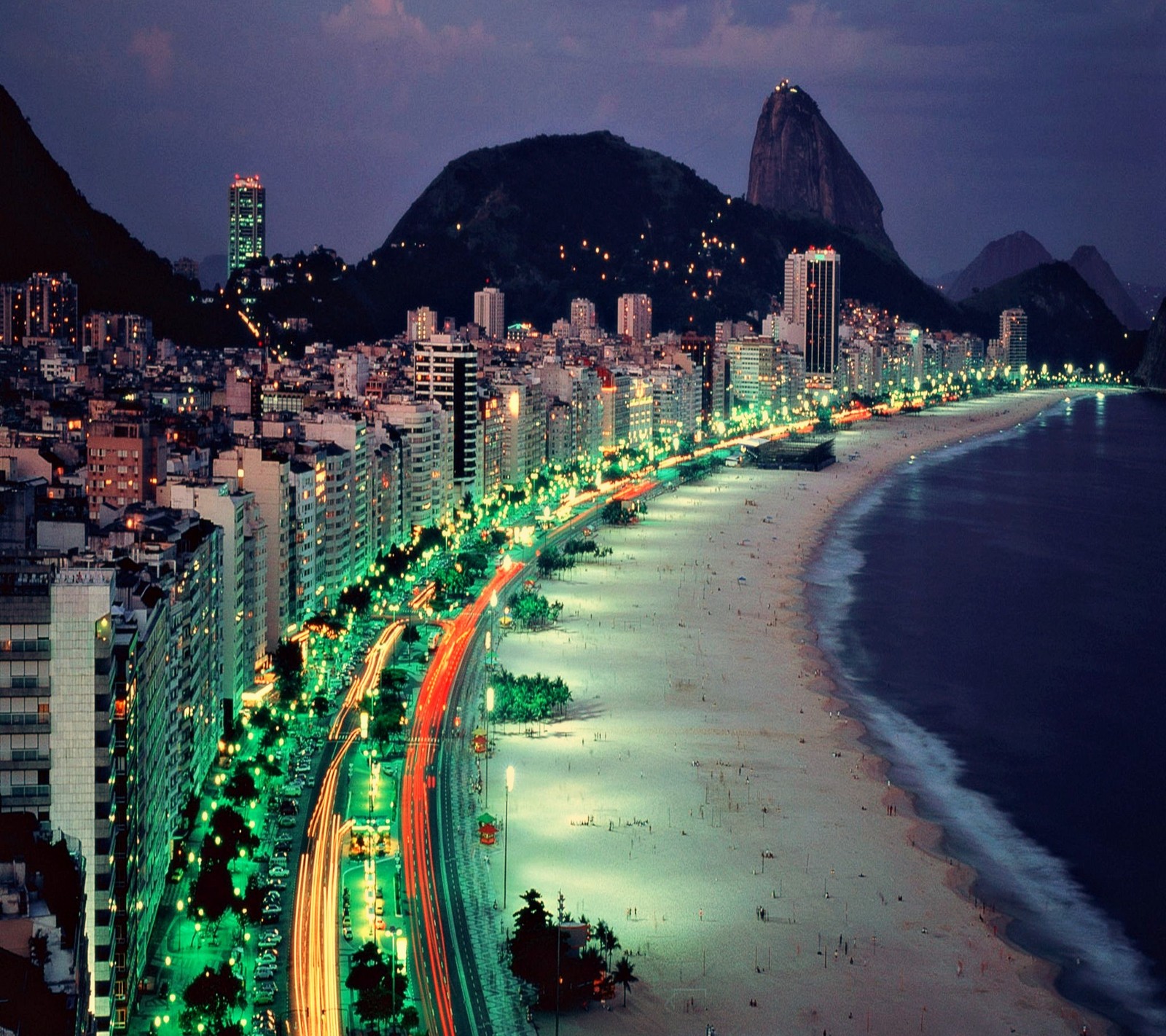 Una vista aérea de una ciudad de noche con una playa y montañas de fondo (playa, ciudad, nuevo, agradable)