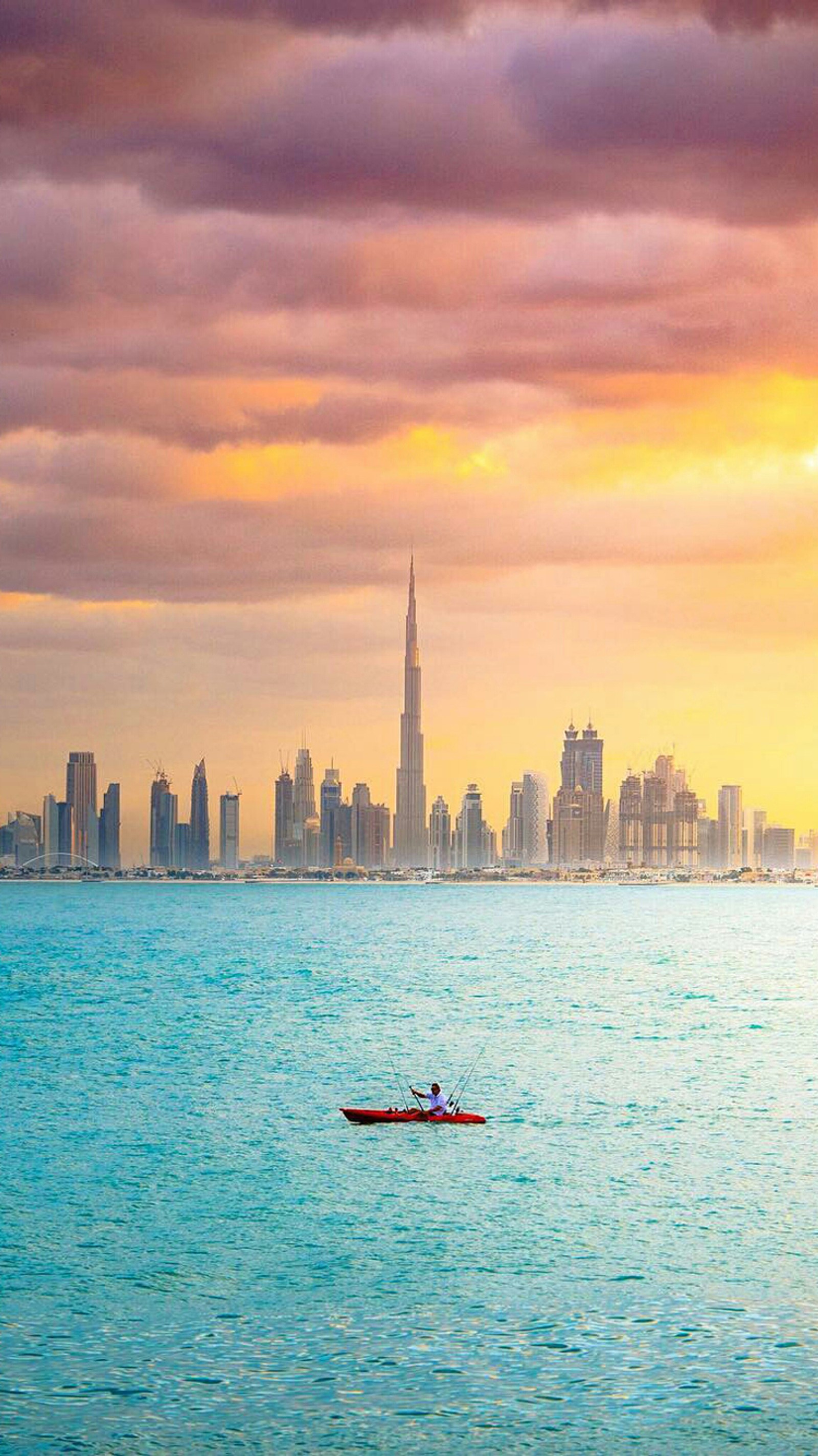 Há um homem em um barco no meio da água (bonito, burj khalifa, cidade, dubai, mar)