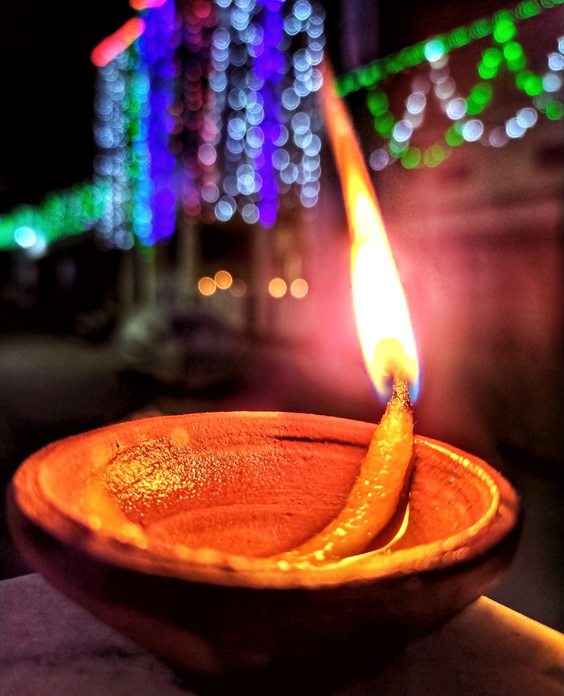 Ярко зажженная свеча в глиняной чаше на столе на улице (день, diwali dia, пламя, счастливый, свет)