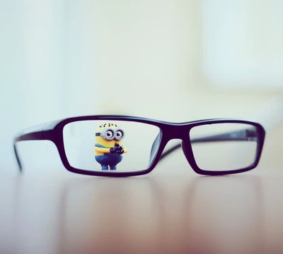 Une figurine de Minion espiègle se reflète dans une paire de lunettes à monture noire.