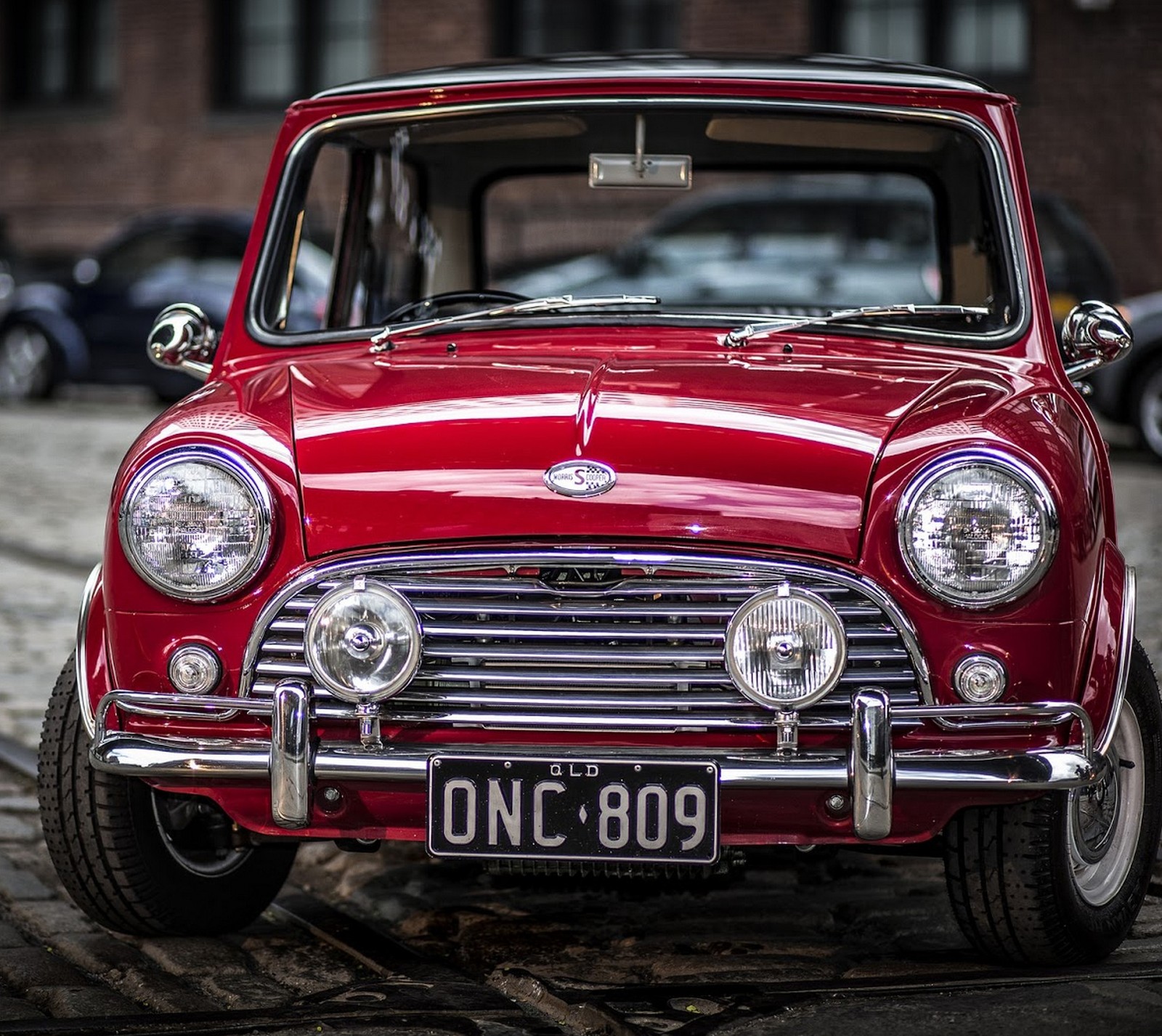 Arafed red car parked on a cobblestone street with a number plate (auto, car, red car, road)