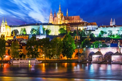 Catedral de San Vito y Puente de Carlos iluminados por la noche con vista al río Vltava en Praga