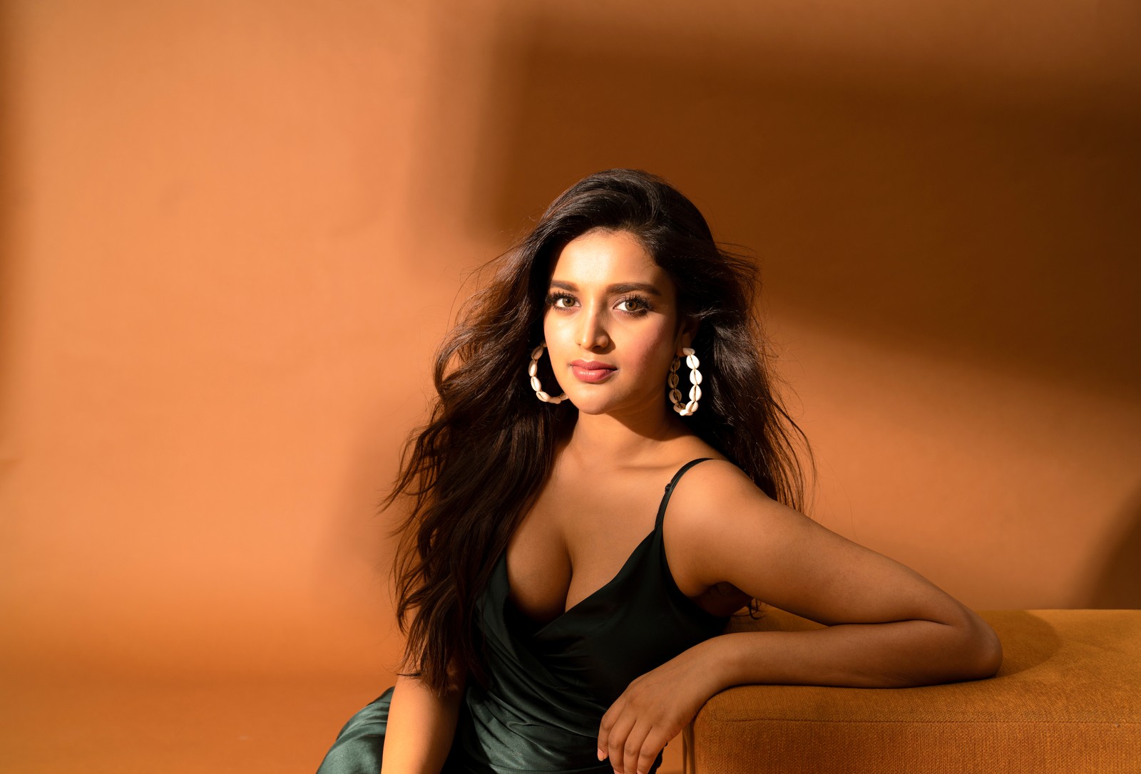 Une femme au long cou en robe verte assise sur un canapé (nidhhi agerwal, 8k, actrice indienne, actrice du sud, 5k)