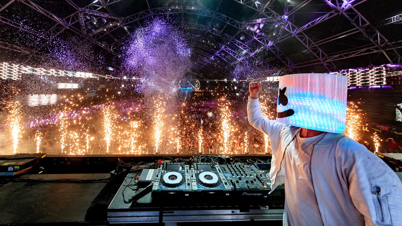 Arafed dj in a white outfit with a hat on his head (concert, electronic dance music, automotive lighting, building, light)