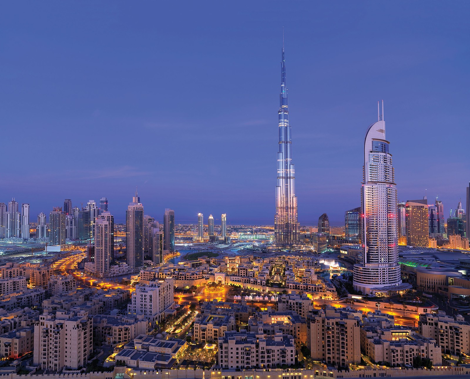 A view of the city skyline at night with the burjra tower in the background (burj khalifa, the dubai fountain, city, cityscape, urban area)