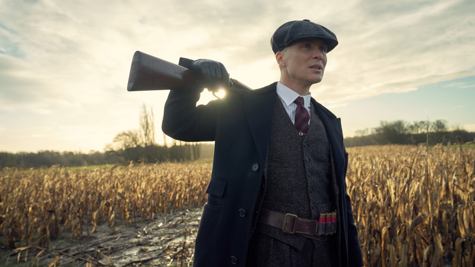 Hombre árabe en un traje y sombrero sosteniendo una pistola en un campo (peaky blinders, series de televisión, cillian murphy, tommy shelby)