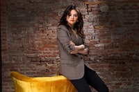 Selena Gomez in a stylish photoshoot, showcasing a chic look against a vintage brick backdrop.