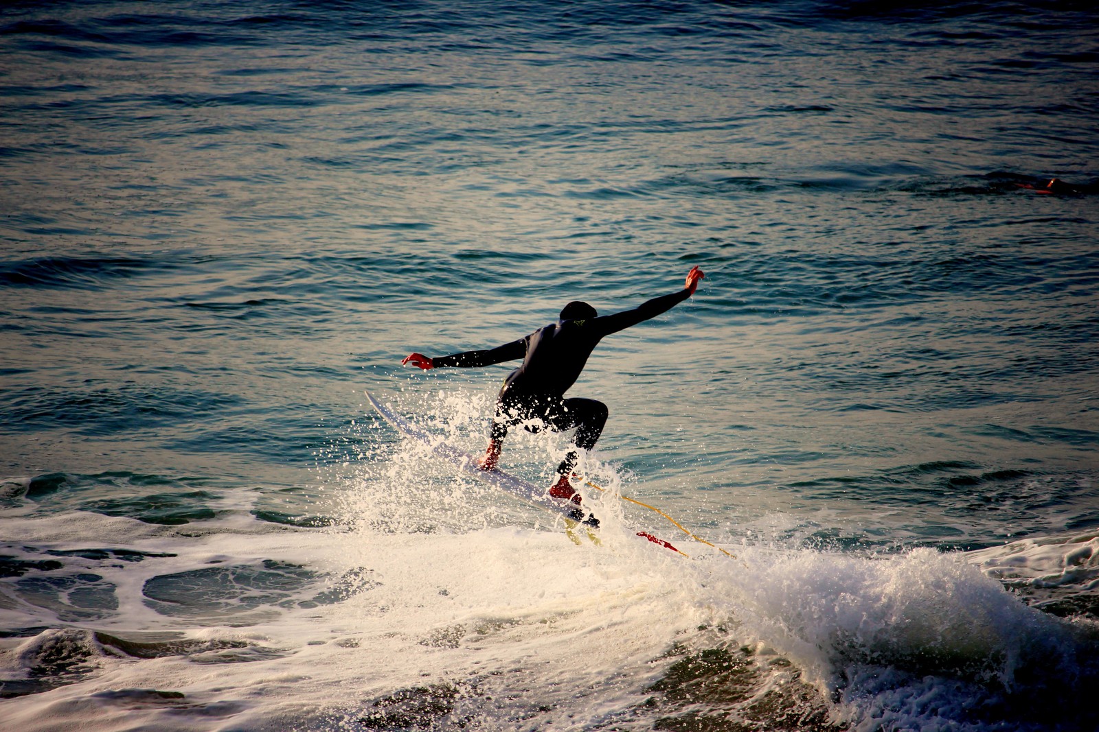 Un surfista en un traje de neopreno montando una ola en una tabla de surf (surfing, tabla de surf, ola, onda de viento, agua)