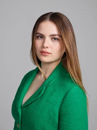 Retrato de Chiara Aurelia, atriz americana, em um vibrante blazer verde, exibindo uma expressão marcante, mas serena.