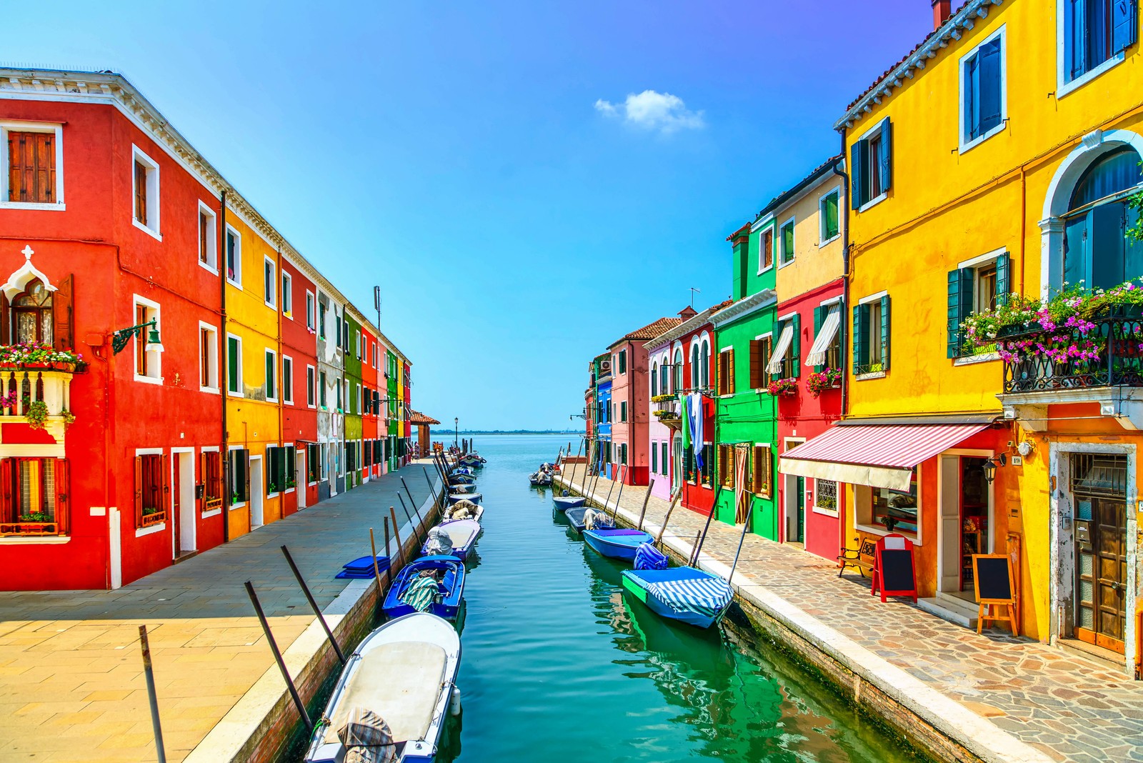 Uma vista de um canal com barcos e edifícios coloridos ao longo (burano, ilha, canal, via navegável, cidade)