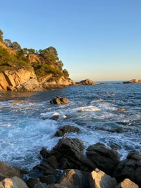 Promontório costeiro ao pôr do sol: Ondas quebram em afloramentos rochosos