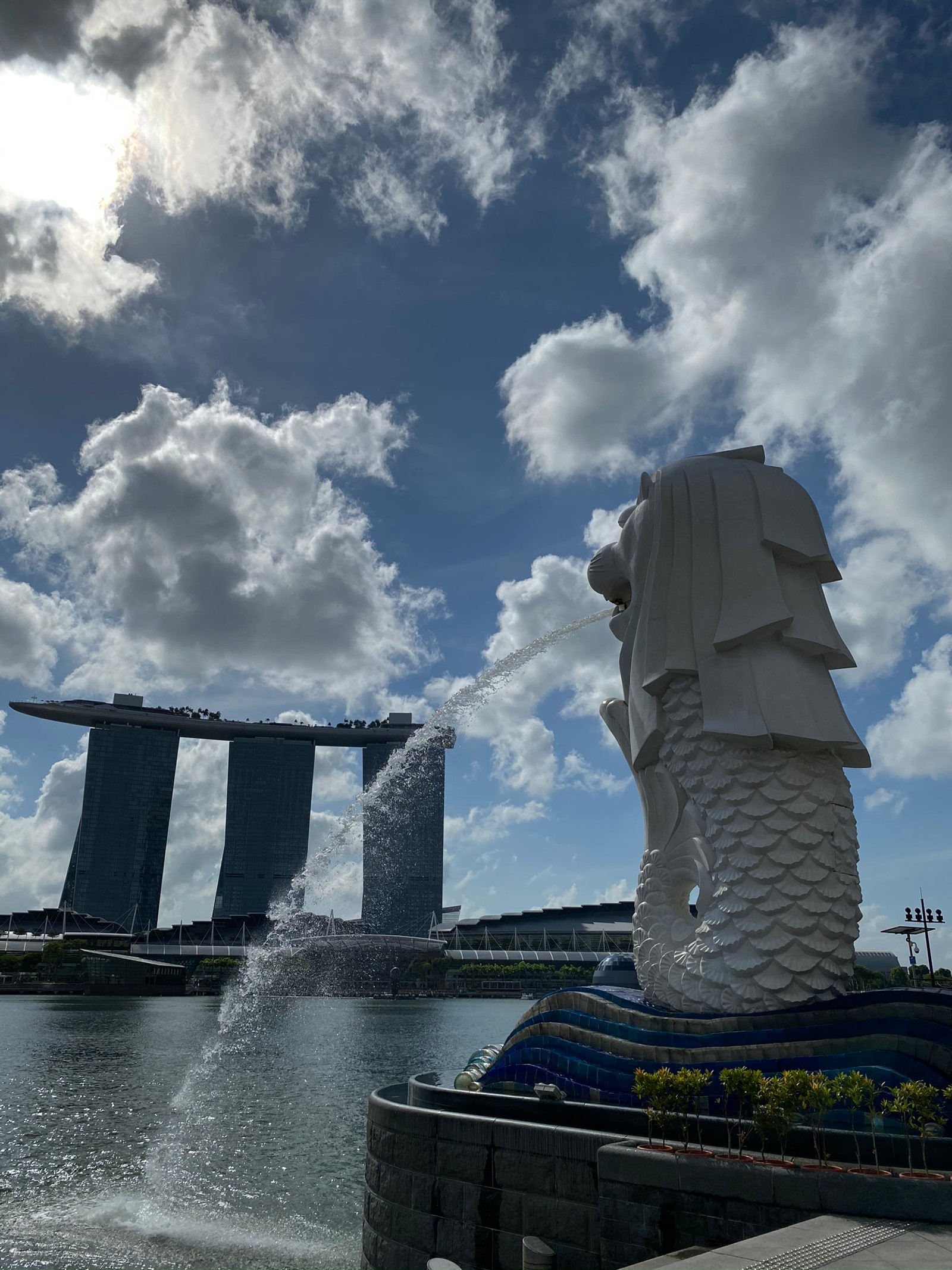 Il y a une statue d'un homme avec un chapeau (singapour, eau, fluide, nuage, point de repère)