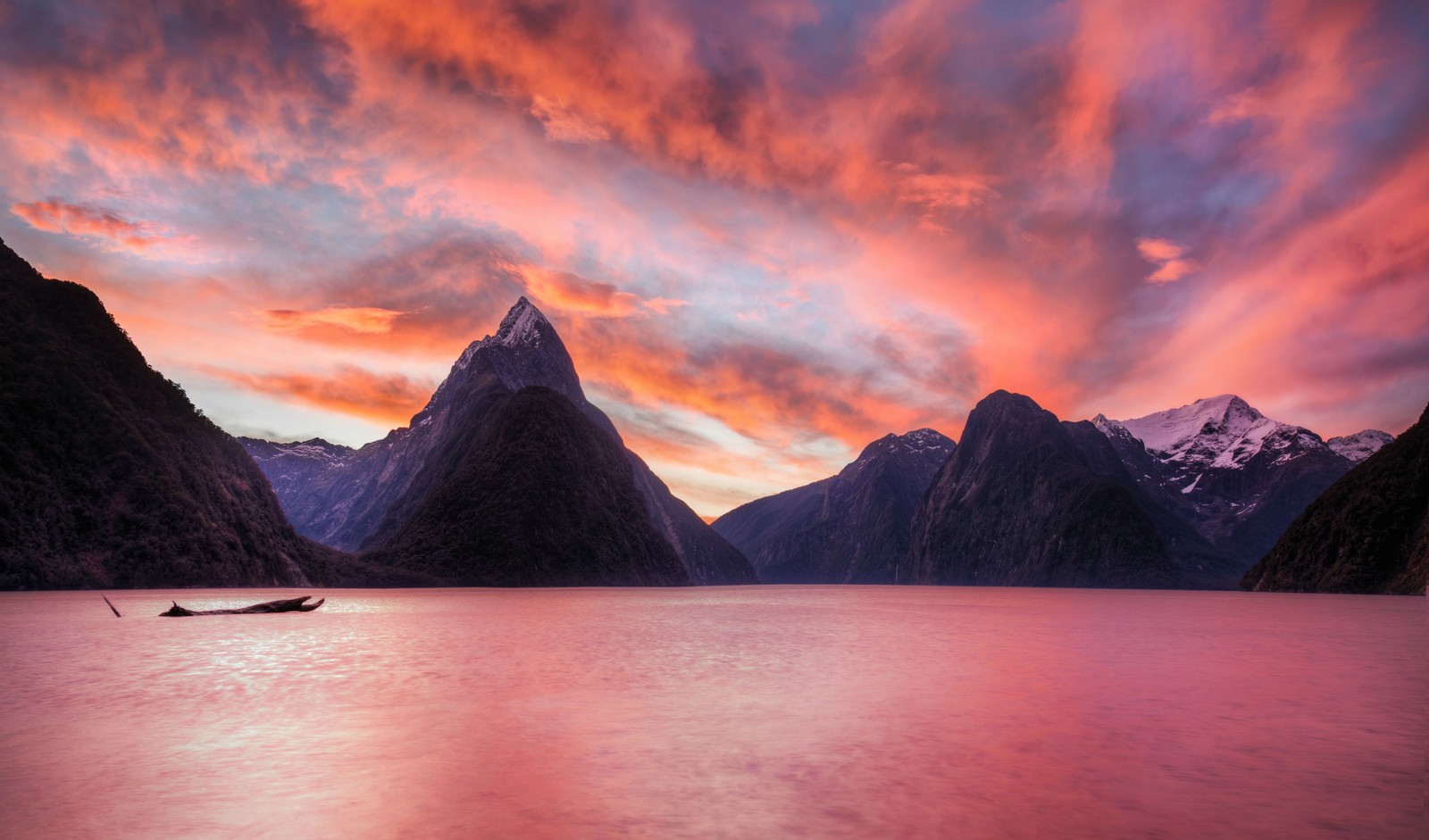 Un bateau flottant dans l'eau près des montagnes au coucher du soleil (milford sound, fjord, nature, formes montagneuses, crépuscule)