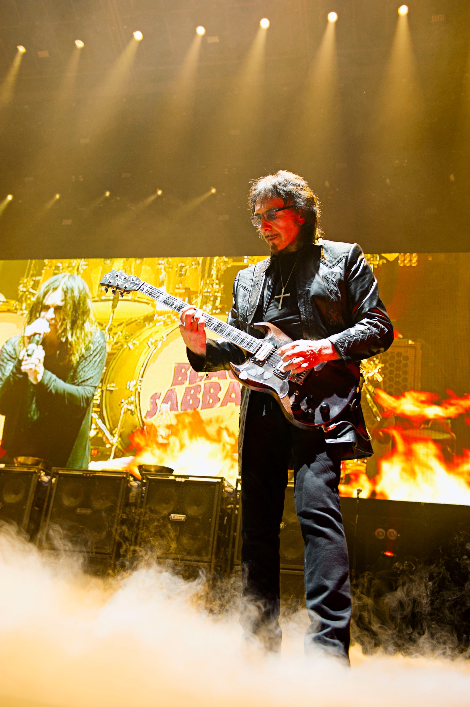 Vista aérea de un guitarrista con chaqueta negra tocando la guitarra en el escenario (concierto, the end tour, black sabbath, heavy metal, desempeño)