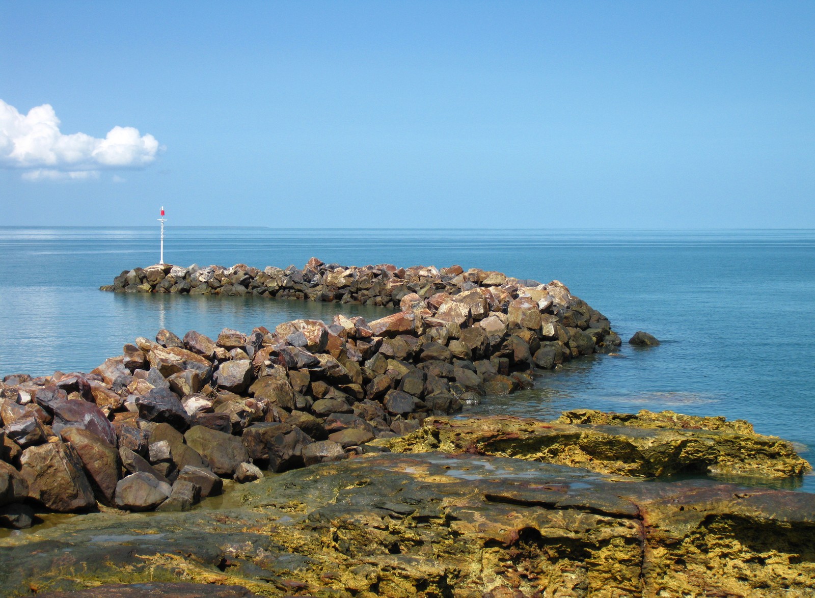 Há uma grande parede de pedra ao lado da água (incrível, azul, água azul, legal, novo)