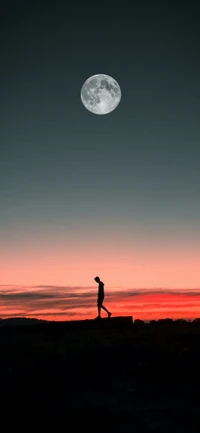 Figura en silueta caminando bajo una luna llena al anochecer