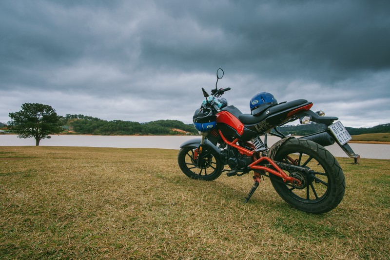 Arafed motorcycle parked in a field with a lake in the background (motorcycle, bicycle, grass, landscape, car)