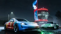 Porsche Taycan Turbo S und Porsche 911 Carrera RSR unter Neonlichtern in einer regnerischen Need for Speed Unbound Umgebung.