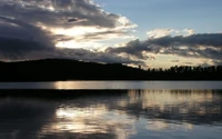 Reflexões noturnas sobre um lago tranquilo sob um céu nublado