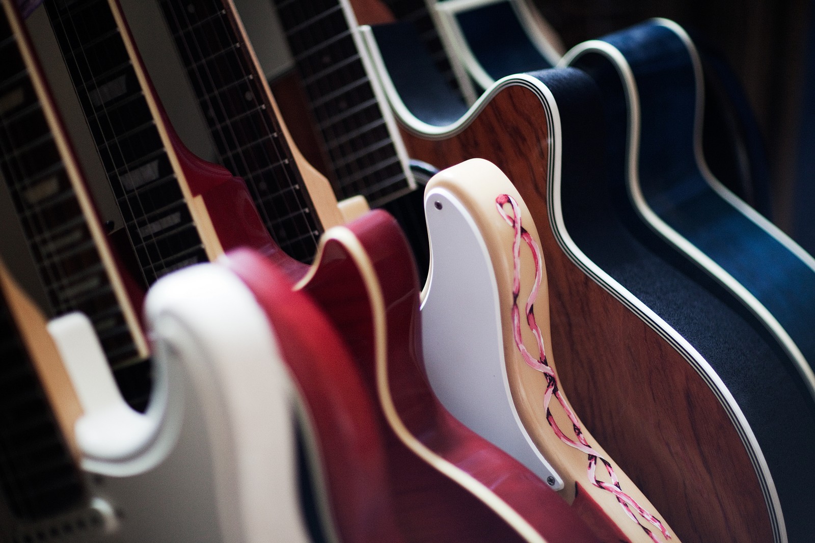 Guitarras alineadas en una fila en una tienda de música (instrumento de cuerda, guitarra, guitarra acústica, instrumentos de cuerda pulsada, instrumento musical)